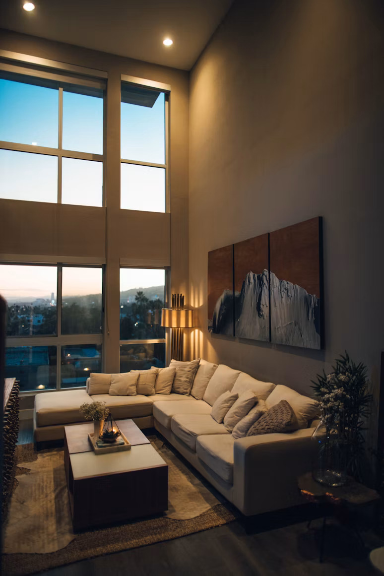 Salón fotografiado para el anuncio: doble altura, ventanal y sofá en L